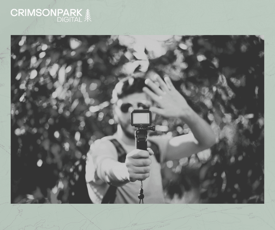 An influencer holds a GoPro camera in front of him while waving from a tourist destination