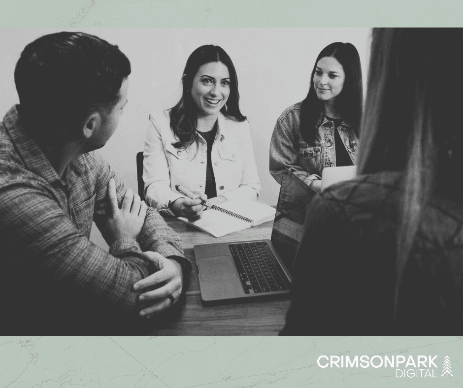 Image shows a team of four marketers sitting around a table, talking strategy