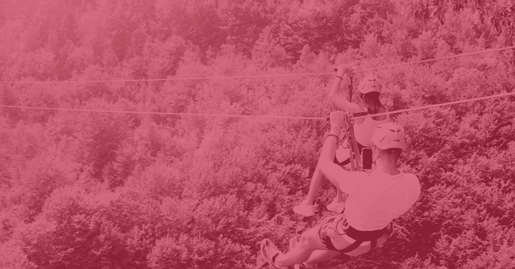 A man records a woman ziplining over a forest